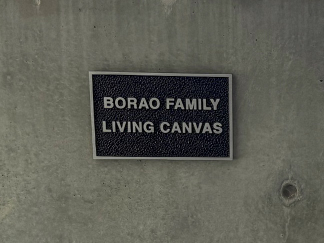 Close-up of the plaque reading “Borao Family Living Canvas” mounted on the concrete wall.
