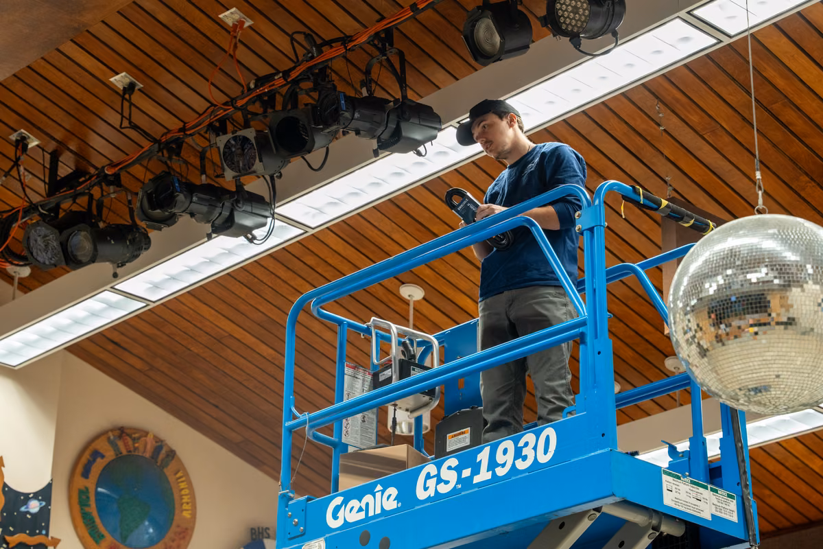 A technician works beside the overhead stage lights in Hodges.