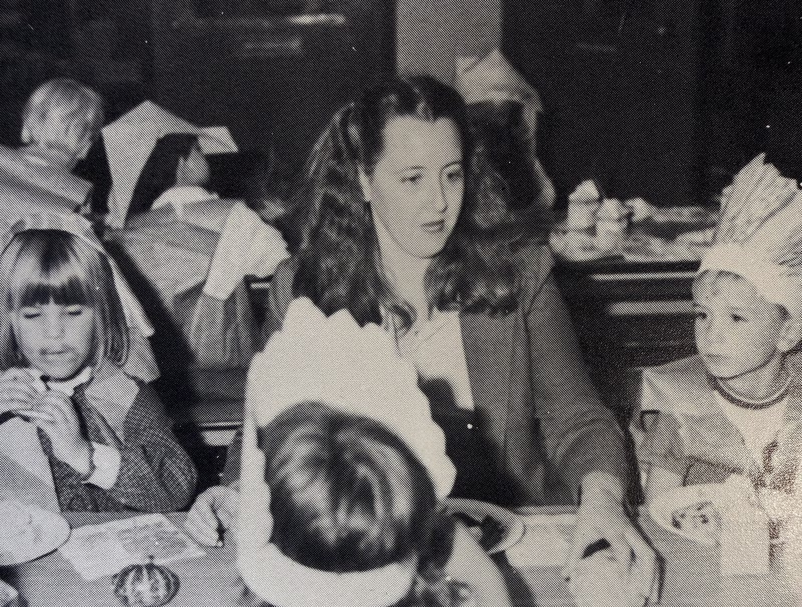 Archival black-and-white photograph of Mrs. DeNisi seated at a classroom table with children wearing paper crowns.