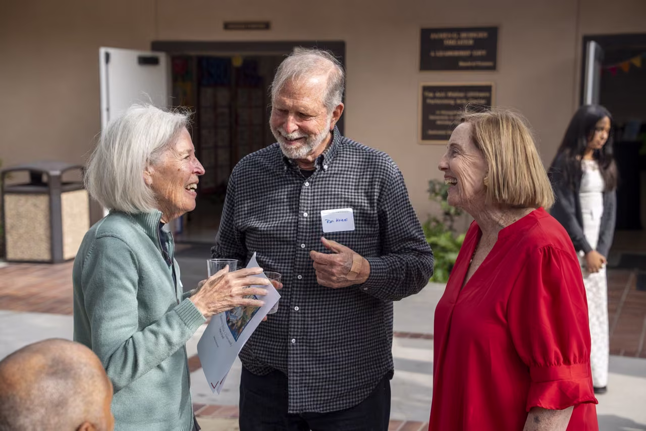 Three guests smile and talk together after the celebration program.