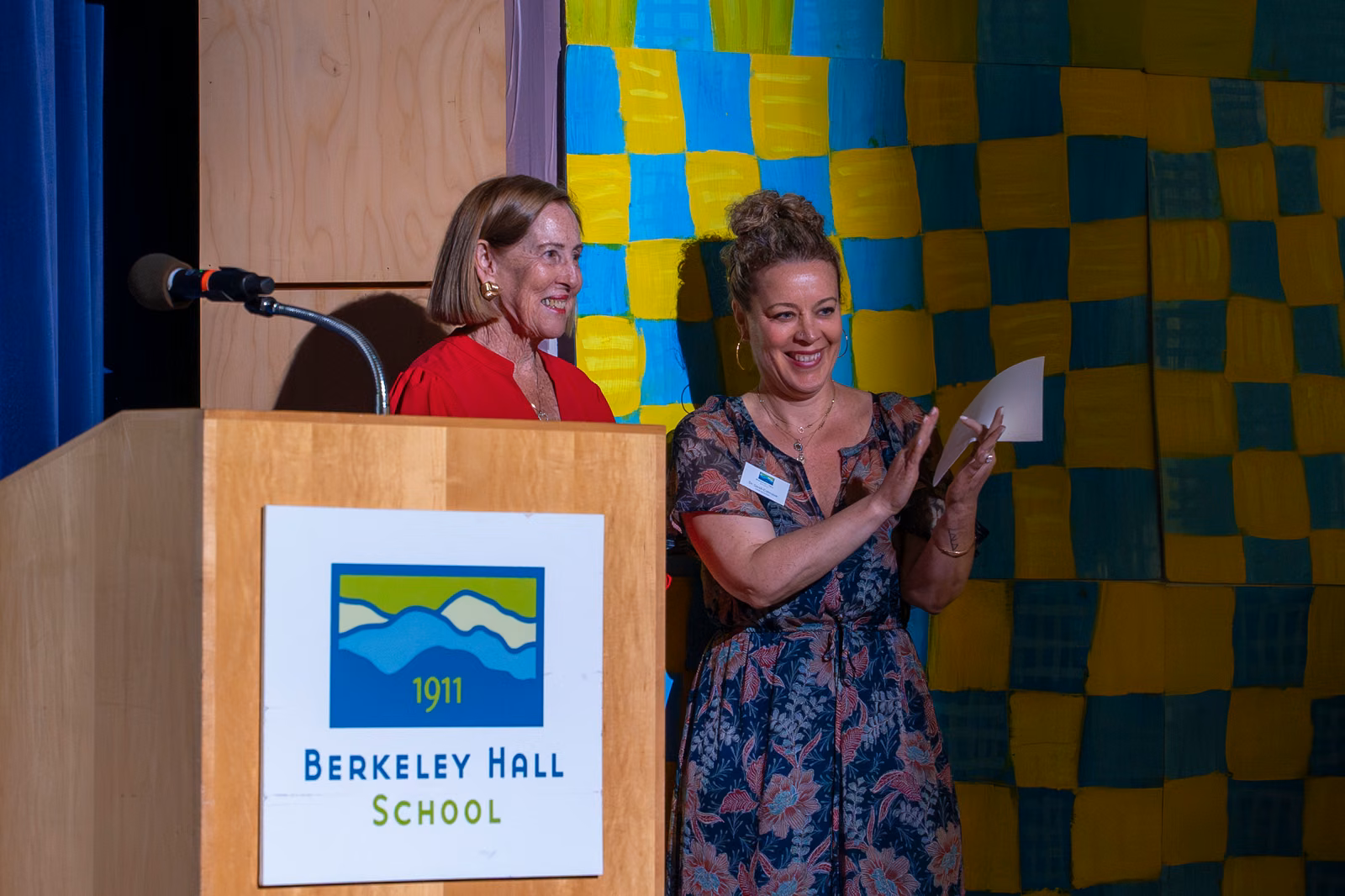 Two women smile at the Berkeley Hall podium during the DeNisi Legacy Celebration.