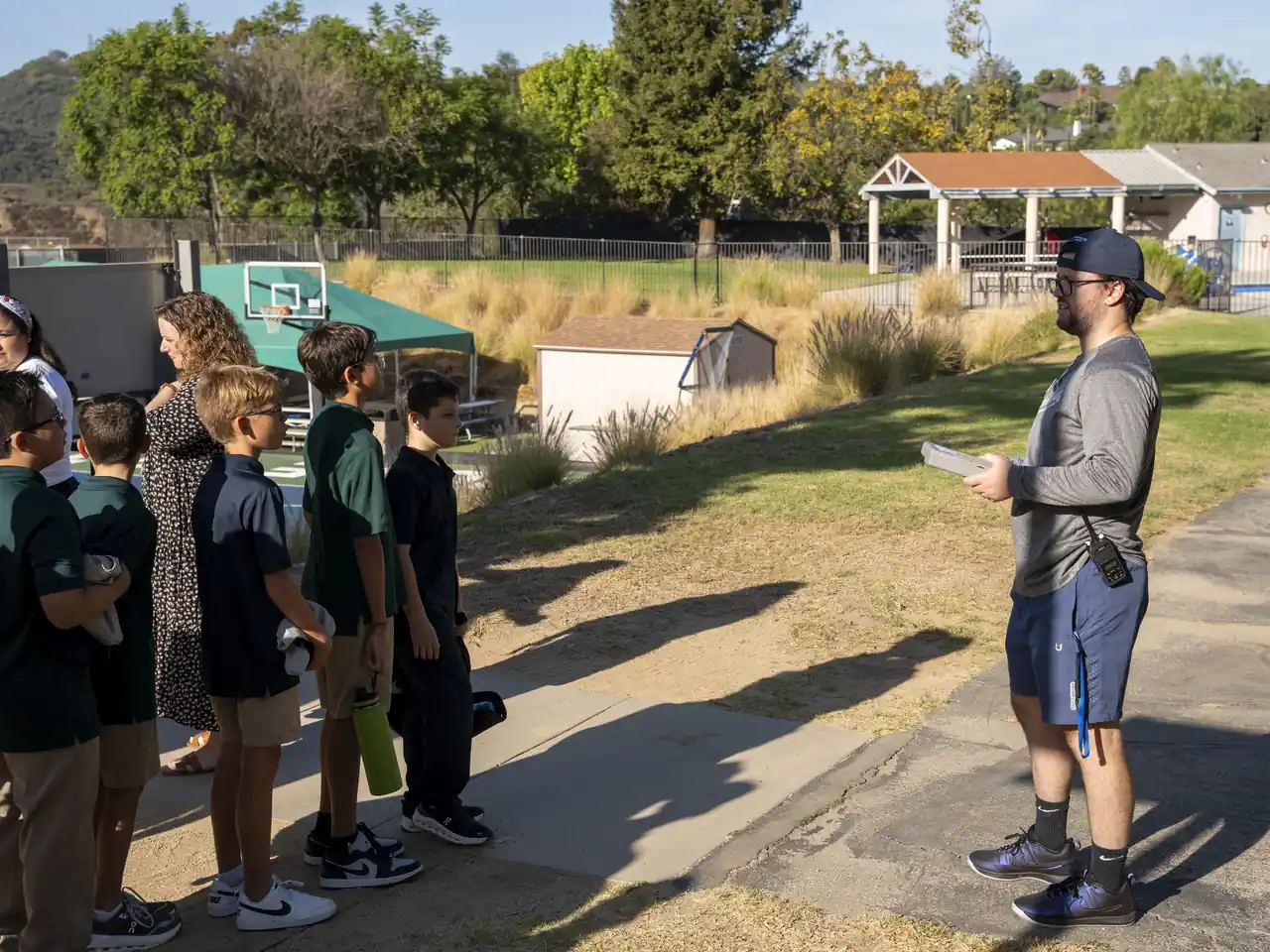 A teacher guides students through an outdoor lesson beside the hillside.
