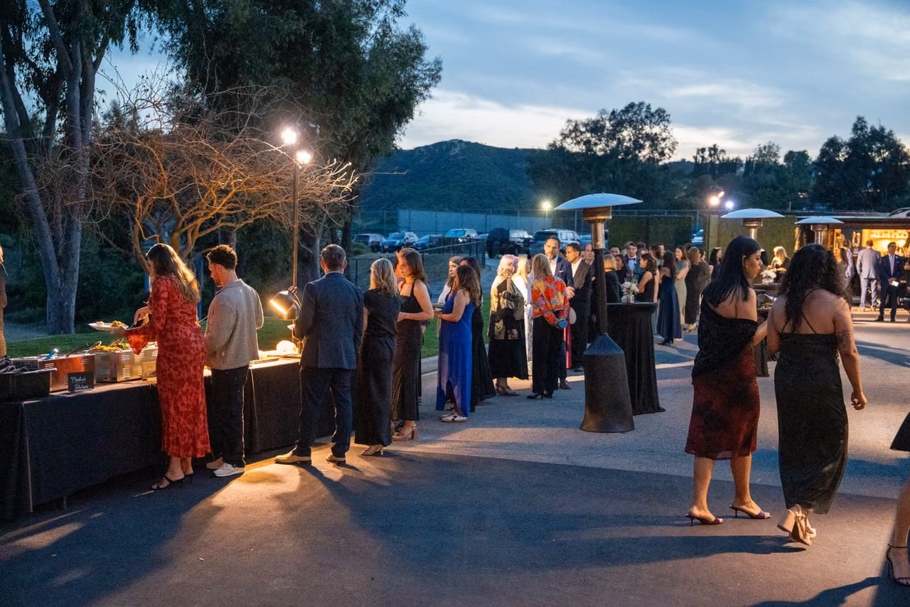 Guests gather outdoors beneath the evening sky at the Bobcat Benefit.