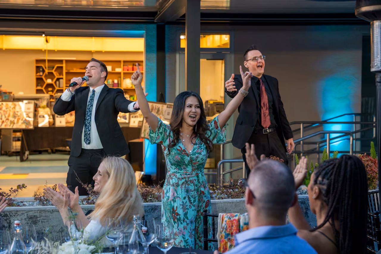 A gala participant raises her arms while people around her applaud.