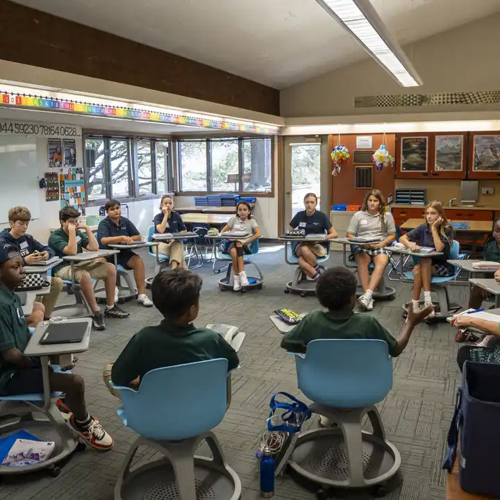 Students and a teacher sit in a classroom discussion circle.