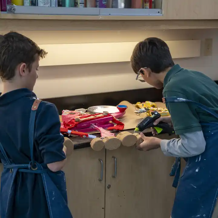 Two students build colorful mixed-media pieces in the art studio.