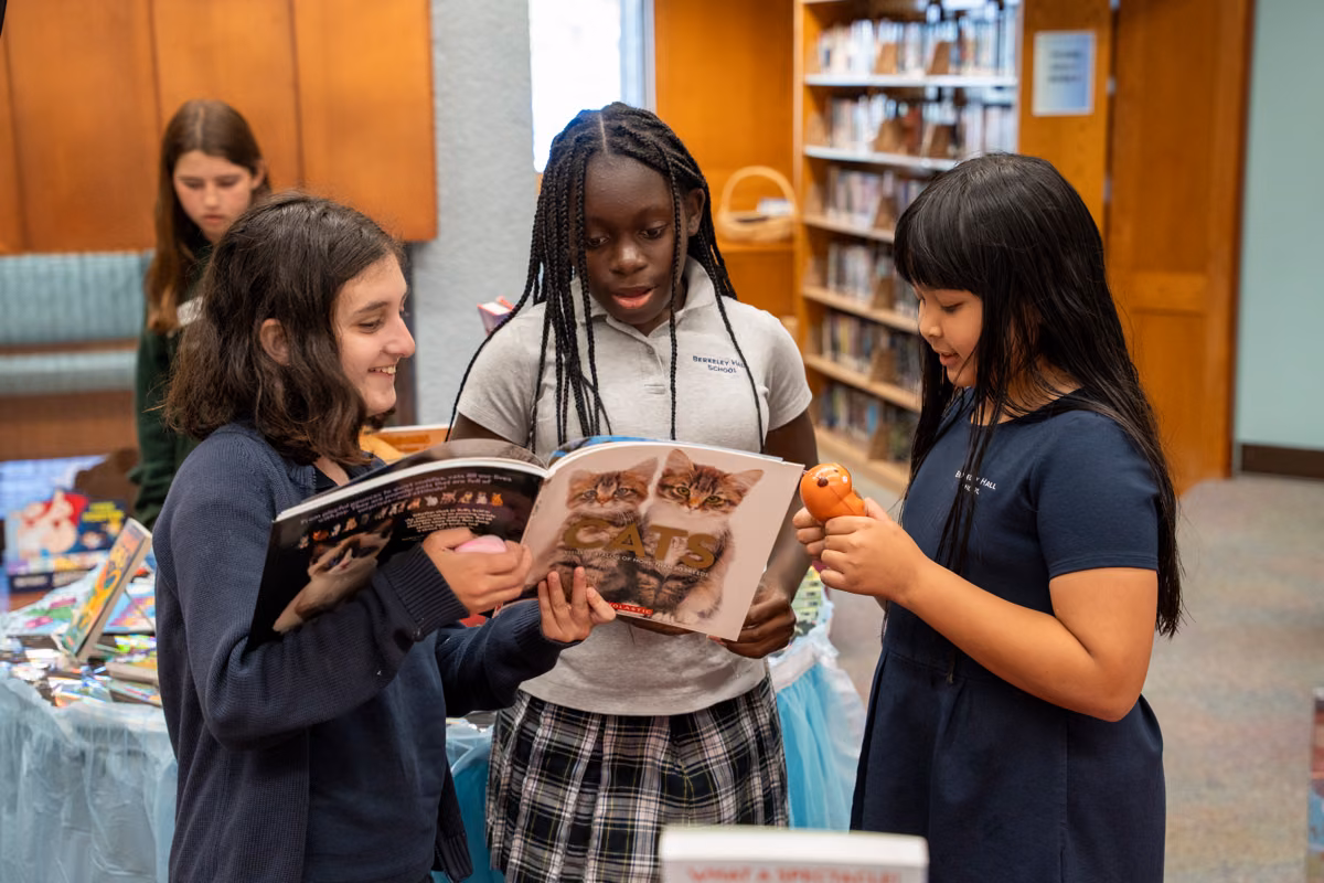 Three students enjoy a book together at the book fair.